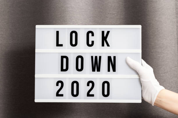 白い手袋の手は、メッセージロックダウン2020とライトボックスを保持します。2020年のワード・オブ・ザ・イヤーはロックダウンです。 - housebound ストックフォトと画像