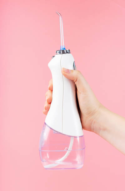 istock Female hand holds a dental irrigator on pink background 1288949211