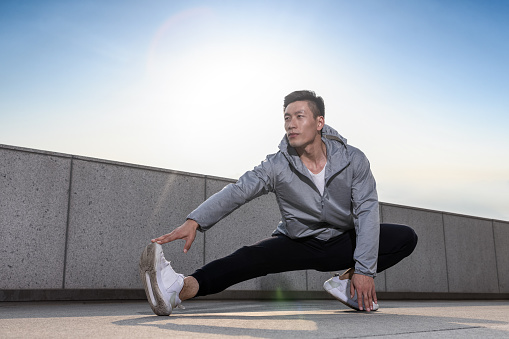 young asian man stretching before running