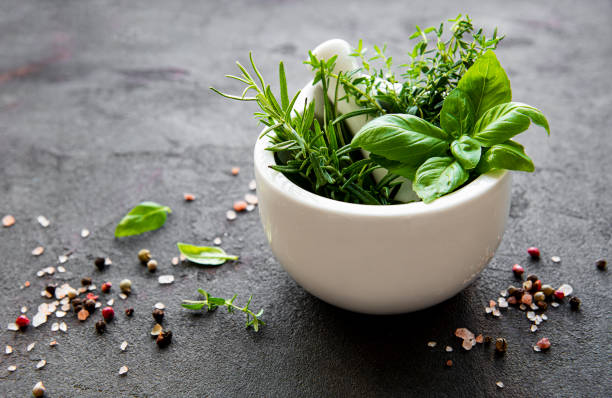 istock Bunch of aromatic herbs in mortar on a black concrete background 1288950170
