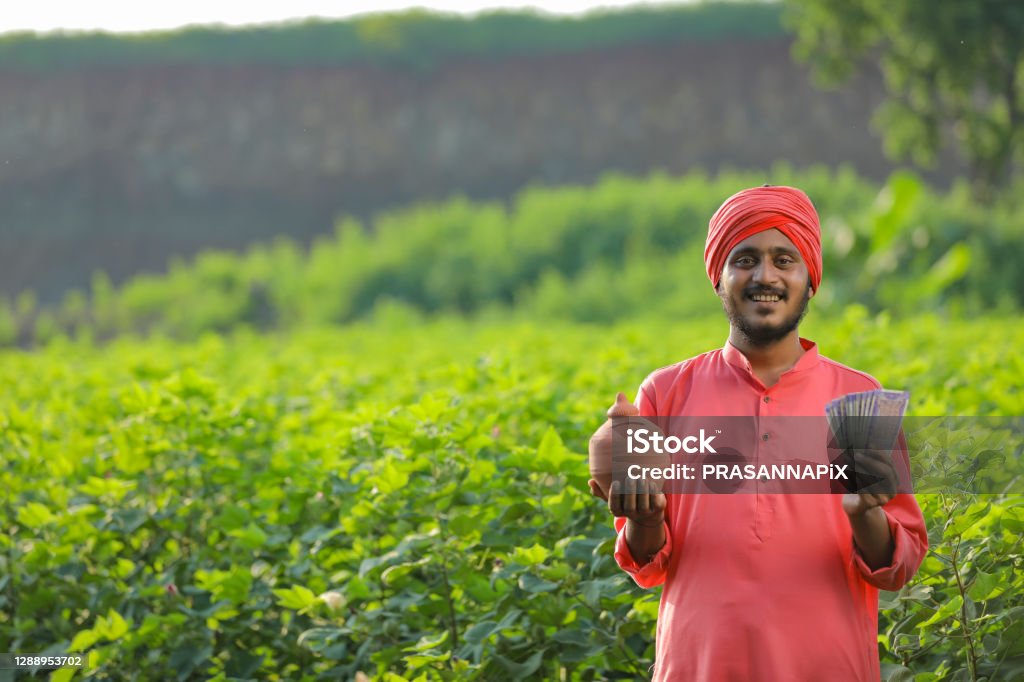 Young Indian farmer holding clay piggy bank and showing money in hand Young Indian farmer holding clay piggy bank and showing money in hand. Culture of India Stock Photo