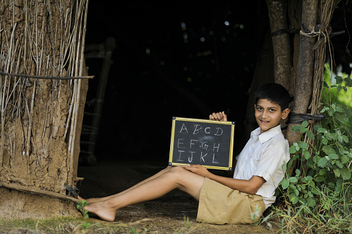 Indian child writing A B C D alphabet on Chalkboard