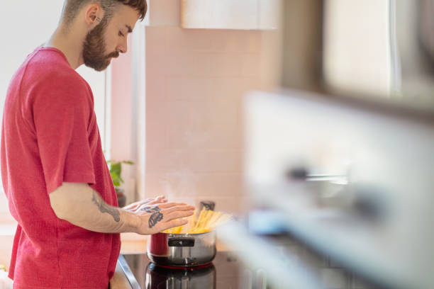 istock Young man pushing spaghetti into a pan with boiling water 1288958733