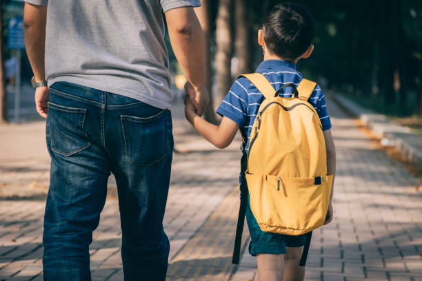 père et fils allant à la maternelle - cartable photos et images de collection