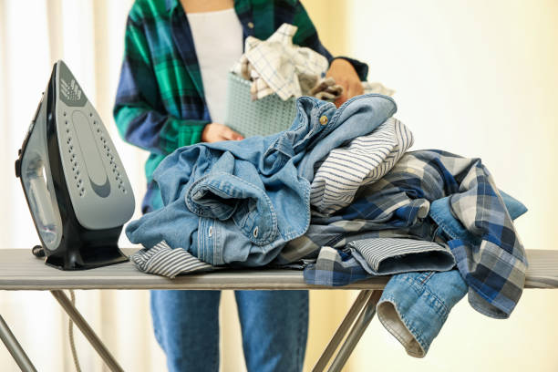 istock Iron on ironing board and woman with basket of laundry 1288962113
