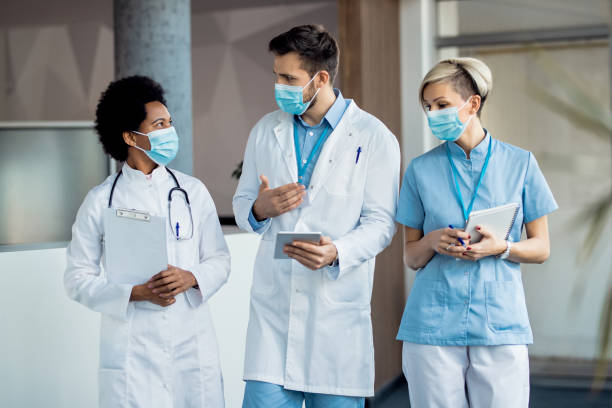 istock Group of medical experts with face masks talking while walking through a hallway. 1288963296