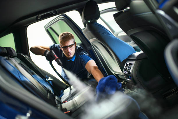 Car detailing service deep interior cleaning. Closeup side view of a young man using fine brush and cleaning AC vents during car interior detailed cleaning. steamed stock pictures, royalty-free photos & images