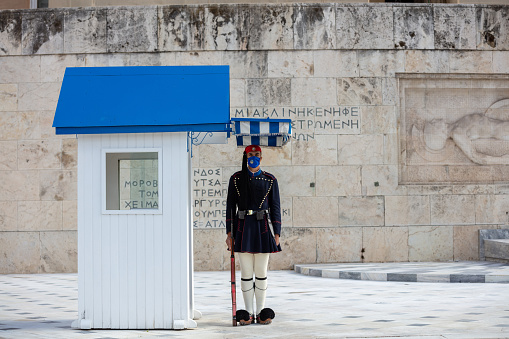 Athens Greece, November 19, 2020. Presidential guard tsolias wearing a COVID 19 protective face mask, standing infront of Greek Parliament building. Tourist attraction at coronavirus days.