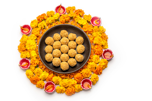 besan laddoo in a plate  kept on Rangoli design made with flower petals of rose and marigold  for Diwali celebration in India