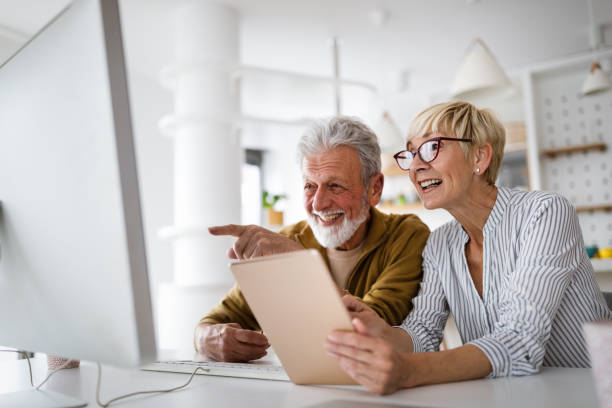 istock Senior woman helping senior man to use computer 1288965895