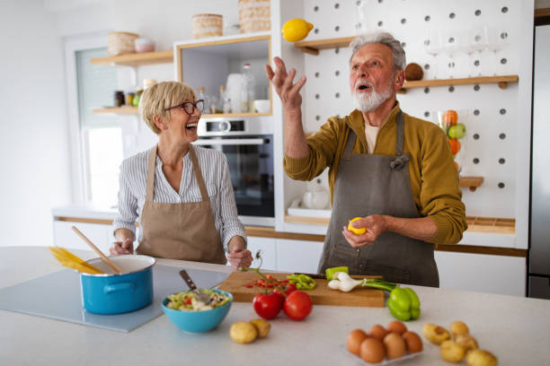 istock Senior couple having fun, cooking together in home kitchen 1288965927