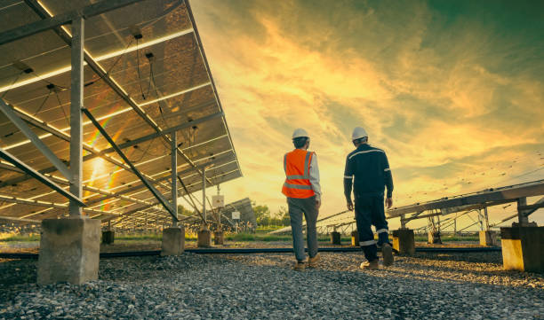 Low angle view of technician walks with investor through field of solar panels, Alternative energy to conserve the world's energy, Photovoltaic module idea for clean energy production Low angle view of technician walks with investor through field of solar panels, Alternative energy to conserve the world's energy, Photovoltaic module idea for clean energy production. alternative lifestyle stock pictures, royalty-free photos & images