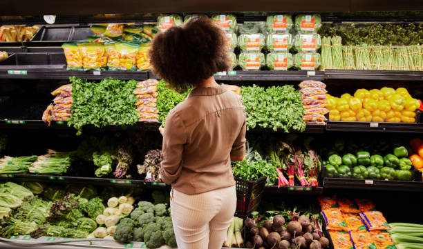 jonge vrouw die de opbrengstsectie in een supermarkt bekijkt - boodschappen stockfoto's en -beelden