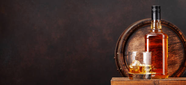 Scotch whiskey bottle, glass and old barrel Scotch whiskey bottle, glass and old wooden barrel. With copy space glass of bourbon stock pictures, royalty-free photos & images