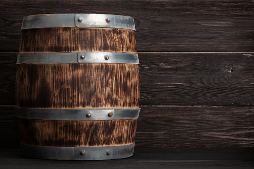 Old wooden barrel for wine or whiskey aging. In front of wooden wall with copy space