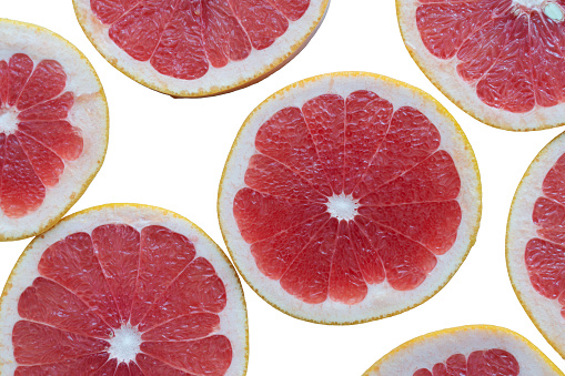 pattern of fresh grapefruit slices on a white isolated background top view
