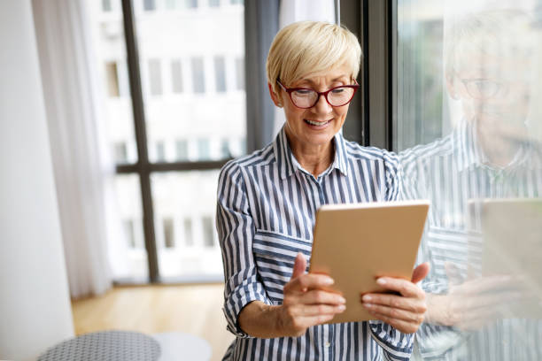 istock Attractive senior woman using a tablet computer relaxing at home 1288972144