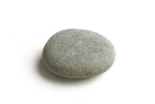 Gray coloured pebbles or gravel horizontal photograph with variety of small and large stones making a rough rustic backdrop with one one big rock in a bed of small stones all over, copy space. Rustic wallpaper template has textured effect and no people.