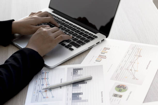 istock A business woman using a laptop And has the company's performance document. 1288974703