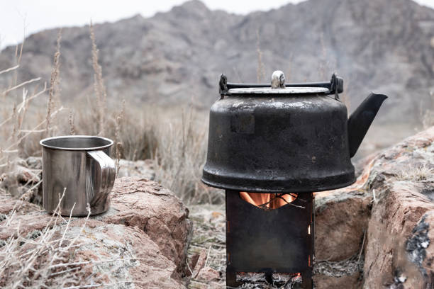 istock Boiling kettle on a portable stove with stainless steel cup. Campfire in mountains. 1288976541