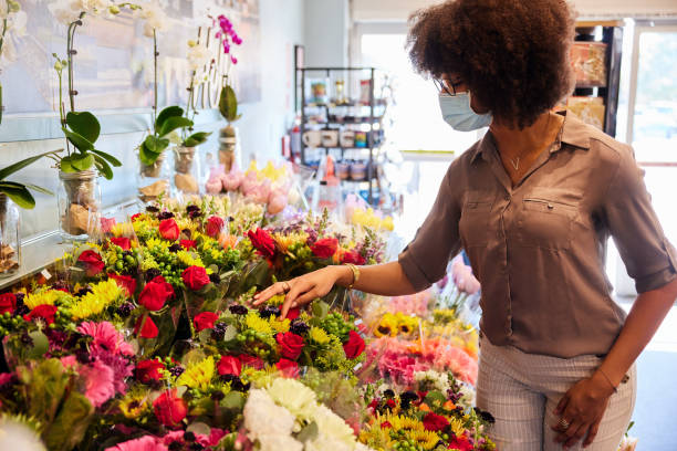 花束を見ているフェイスマスクを身に着けている女性 - florist supermarket flower bouquet ストックフォトと画像