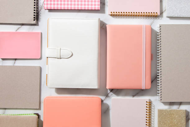 istock Creative flat lay of workspace desk with neatly arranged various coral, grey colored diary and pens 1288985572