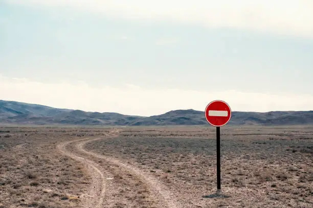 Travel concept background. No entry sign on gravel road in steppe. Wrong way, wrong direction concept. Wrongway road sign gravel, great design for any purposes.