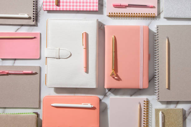 istock Creative flat lay of workspace desk with neatly arranged various coral, grey colored diary and pens 1288986175