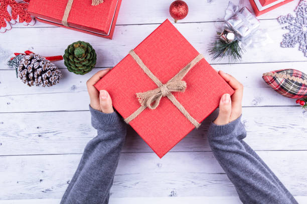 hands of the girl holding the red gift box and new year gifts stock photo