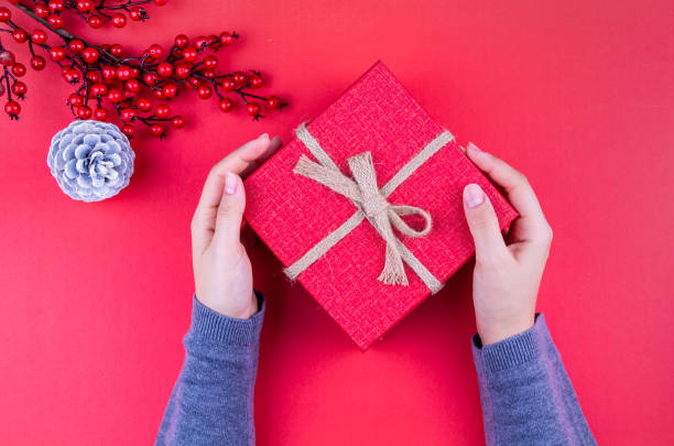 Christmas background. Gift boxes with colorful shiny Christmas decorations, cones, star and ball on the whiteboard, and the girl is holding the new year gift box. stock photo
