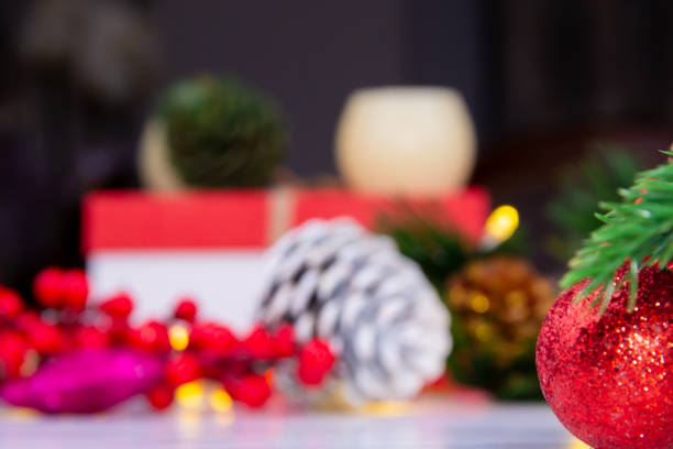 bright red christmas ball standing in front of pine tree light and various christmas decorations stock photo