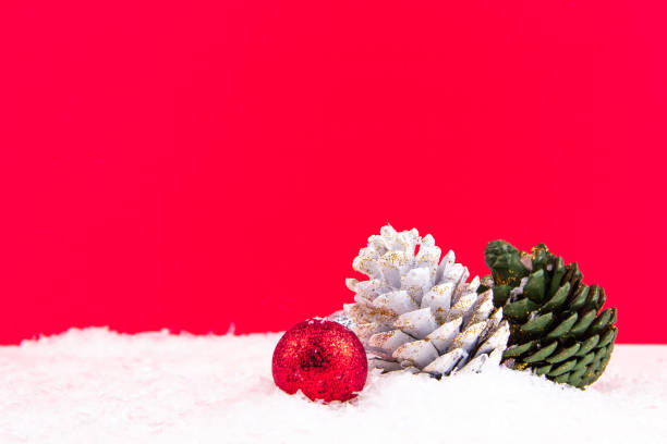 colorful pine cones on red background and snowy backdrop for new year celebration stock photo