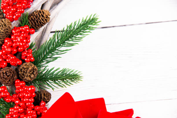 Close up Christmas branch made of cones, red Butcher's Broom and pine branches on a white wood background stock photo