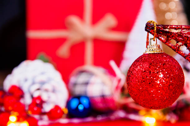 Close up of a bright silvery red Christmas ball in front of colorful and bright Christmas decorations stock photo