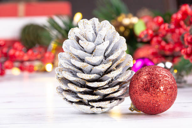 golden silvery pine cone and red glitter new year ball on white wood ground with light stock photo