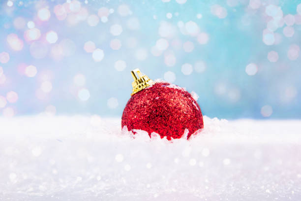 shiny New Year tree ornament red ball stuck in snow stock photo