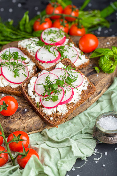 istock cottage cheese on a cracker, several sliced black bread, with radish sliced into wedges with dill, top and side shot, on a wooden cutting board, on a white isolated background 1288988793