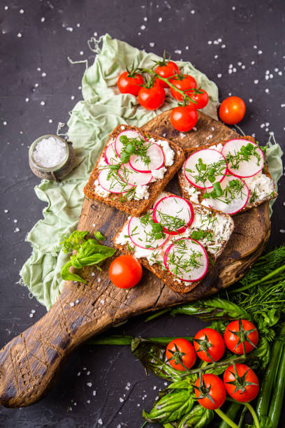 istock cottage cheese on a cracker, several sliced black bread, with radish sliced into wedges with dill, top and side shot, on a wooden cutting board, on a white isolated background 1288988810