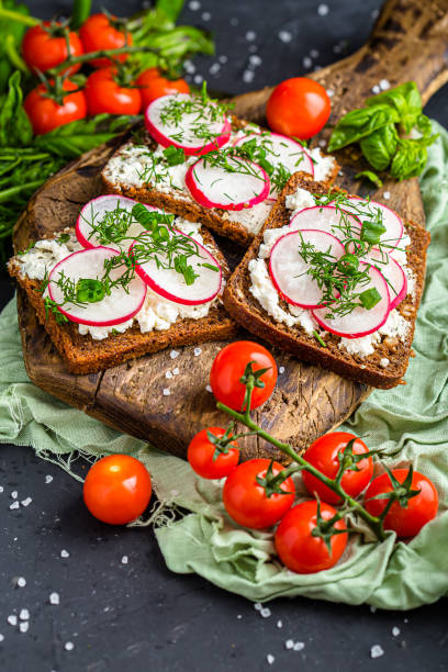 istock cottage cheese on a cracker, several sliced black bread, with radish sliced into wedges with dill, top and side shot, on a wooden cutting board, on a white isolated background 1288988811