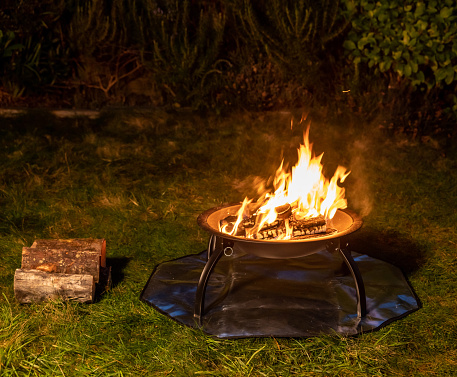Fire pit on a safety mat to protect the grass
