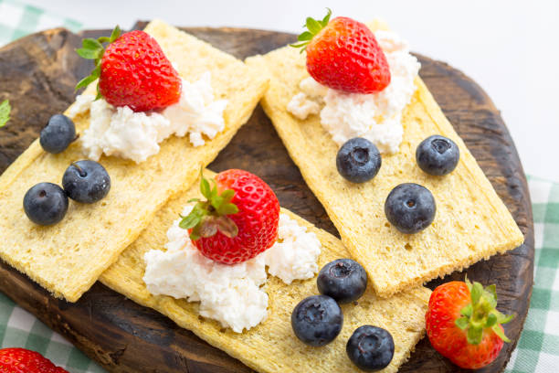 istock cottage cheese on several crackers, crisps with berries, strawberries and blueberries with mint, top and side shot, on a wooden cutting board, on a white isolated background 1288989927