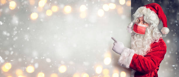 istock Santa Claus With Protective Mask Pointing Blank Billboard 1288990064