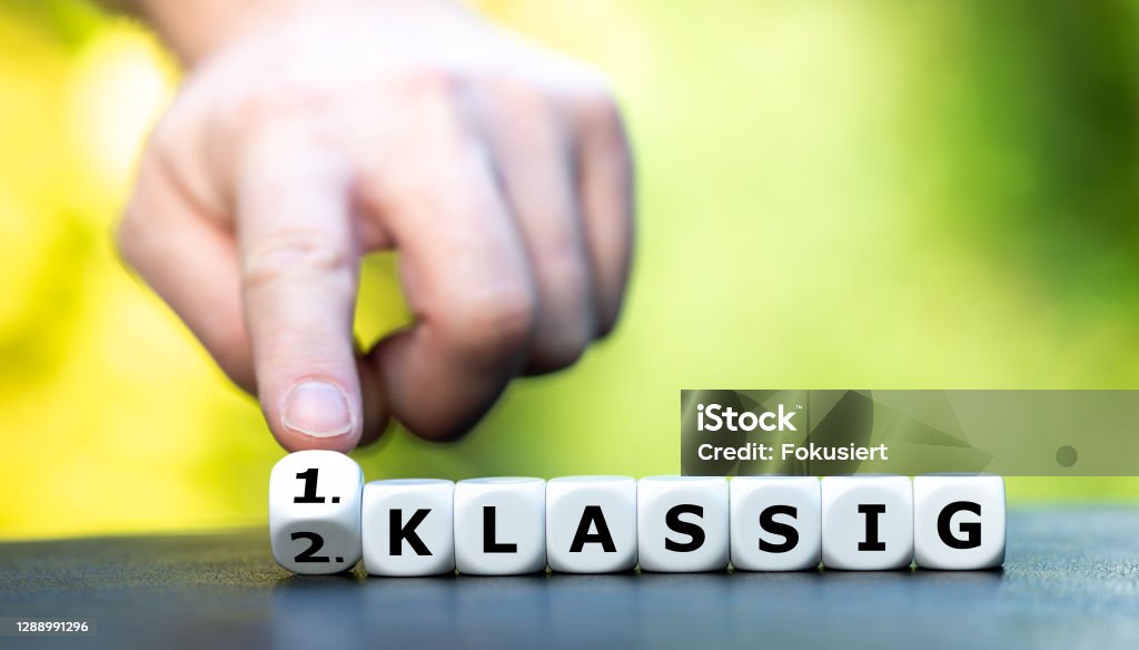 Hand turns dice and changes the German expression "2. klassig" (second class) to "1. klassig" (first class). Advertisement Stock Photo