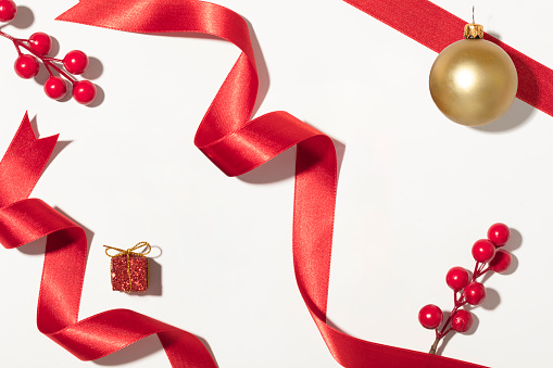 Winter Celebration Setup: Top view of various tree ornaments, orange and gold balls, sparkling stars, snowflake decor, and confetti scattered on pastel backdrop. Perfect for holiday greetings or ads