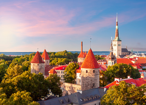 Classic Tallinn cityscape with St. Olav's church and old town walls and towers at sunset, Estonia