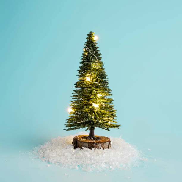 istock Christmas layout made with miniature pine tree, light bulbs and snow on pastel blue background 1288994533