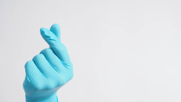 Male model's hand with glove is doing mini heart hand sign on white background.