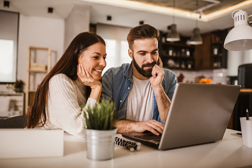 Happy couple enjoying work from home. Happy couple doing business together working at home on the laptop.