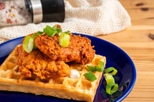 comida callejera casera de estilo sureñoamericano fresca frita crujiente alitas de pollo apiladas con salsa picante de chile rojo búfalo y jarabe de arce dulce waffle - waffle chicken fried chicken food fotografías e imágenes de stock