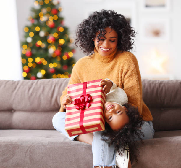 istock Happy ethnic woman and boy with Christmas present playing on sofa 1288998878